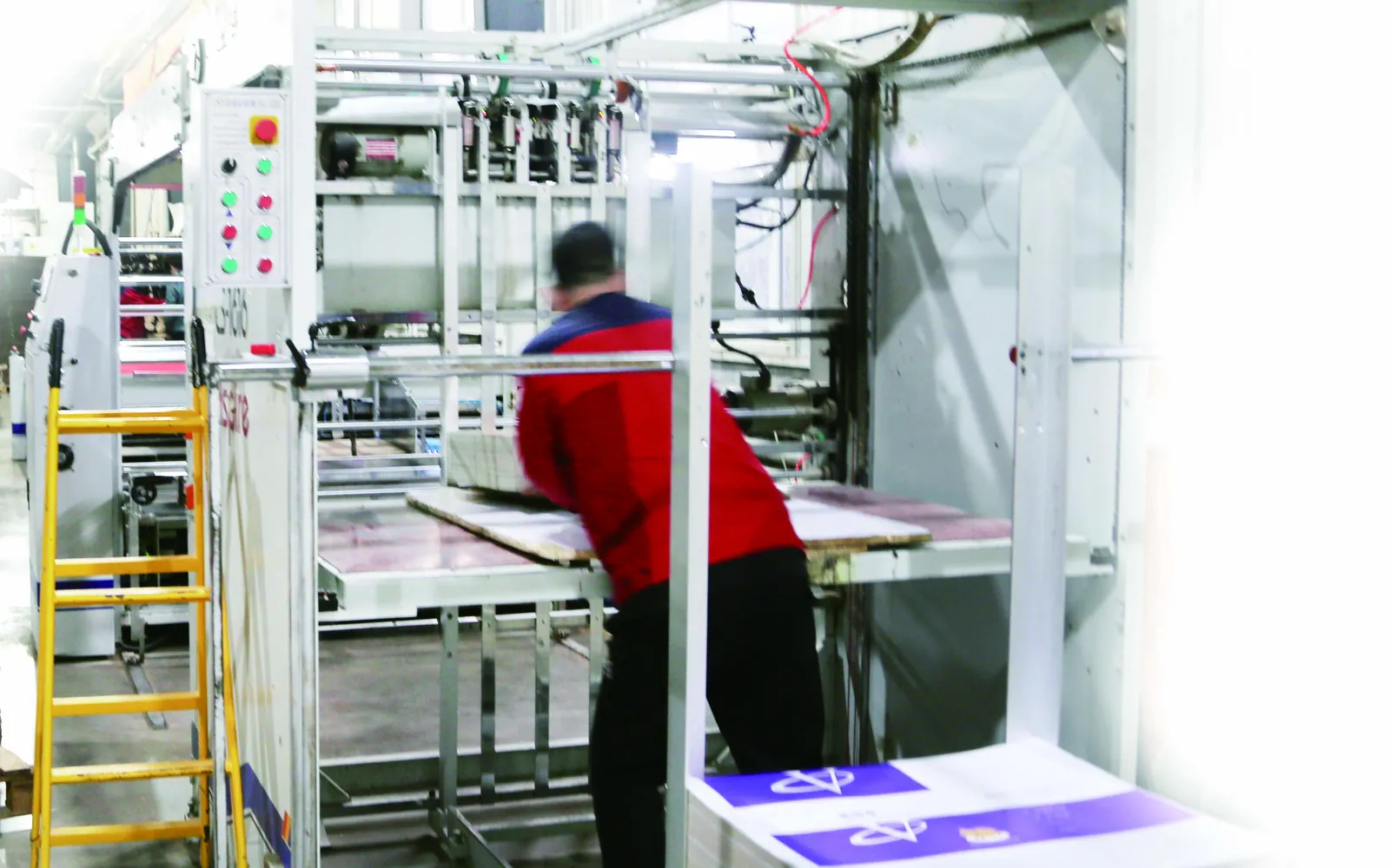 Operator running an automatic sheet mounting machine for paper packaging