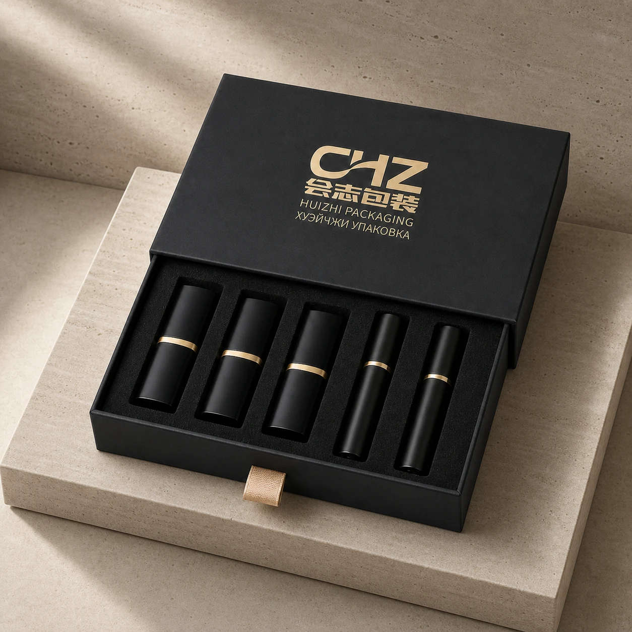Open matte black pull-out lipstick box with five black cosmetic tubes, gold accents, and a fitted black insert.