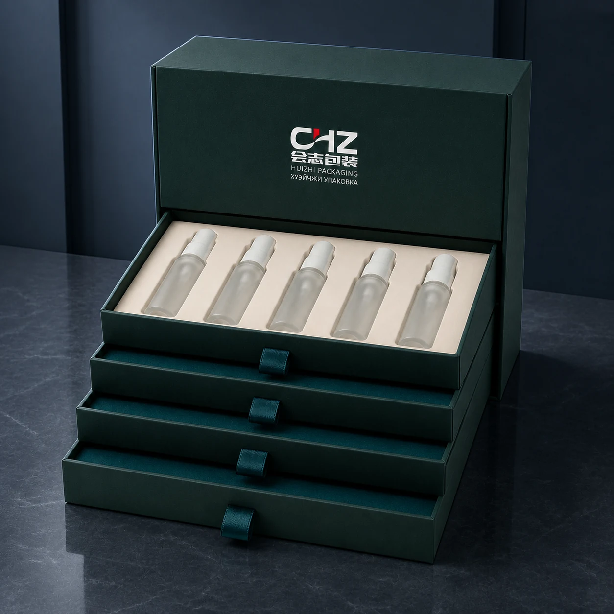 Deep teal tiered cosmetic box with five frosted serum bottles in an ivory tray above four pull-out drawers.