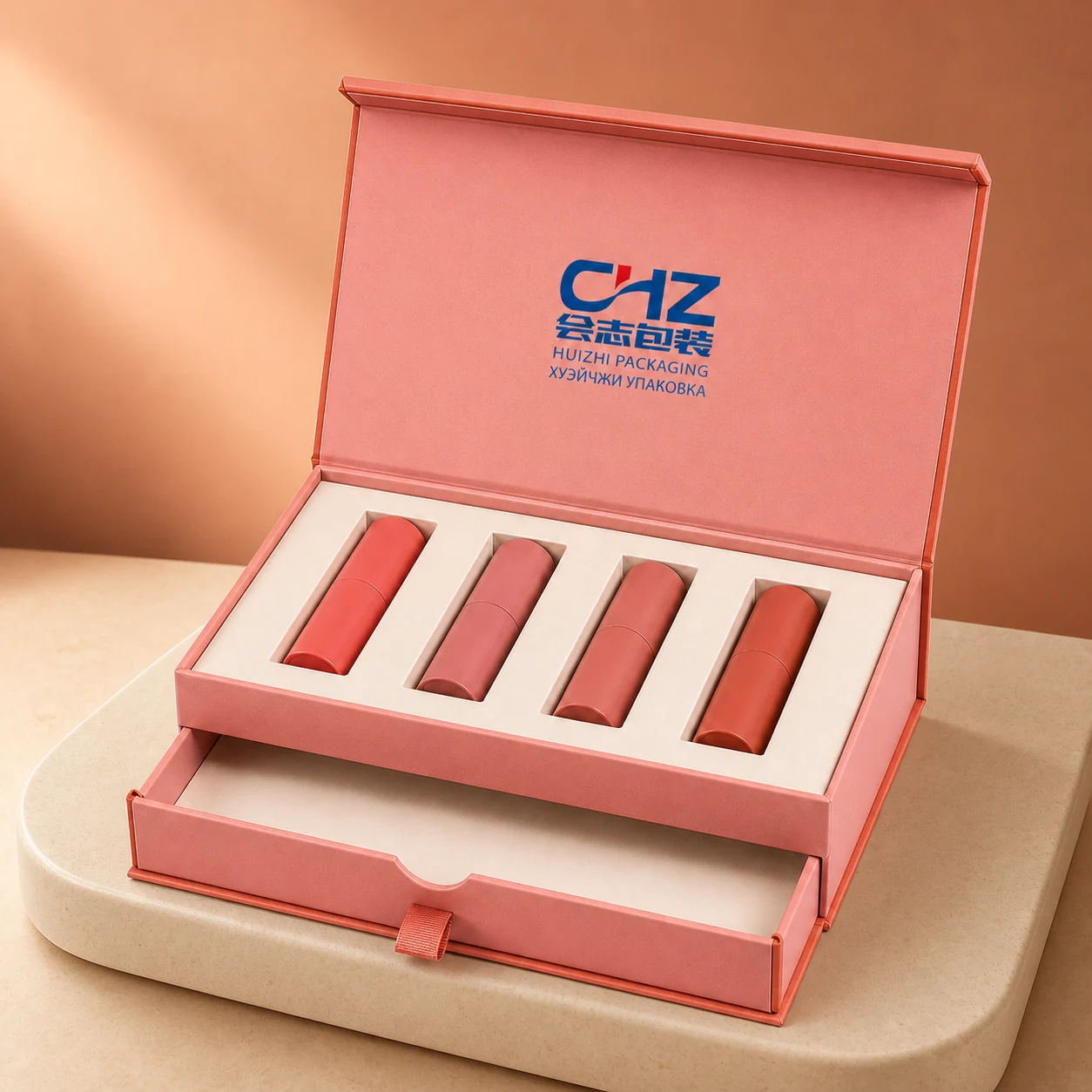 Open coral pink two-level makeup box with four lipstick tubes in an ivory tray and a lower pull-out drawer.