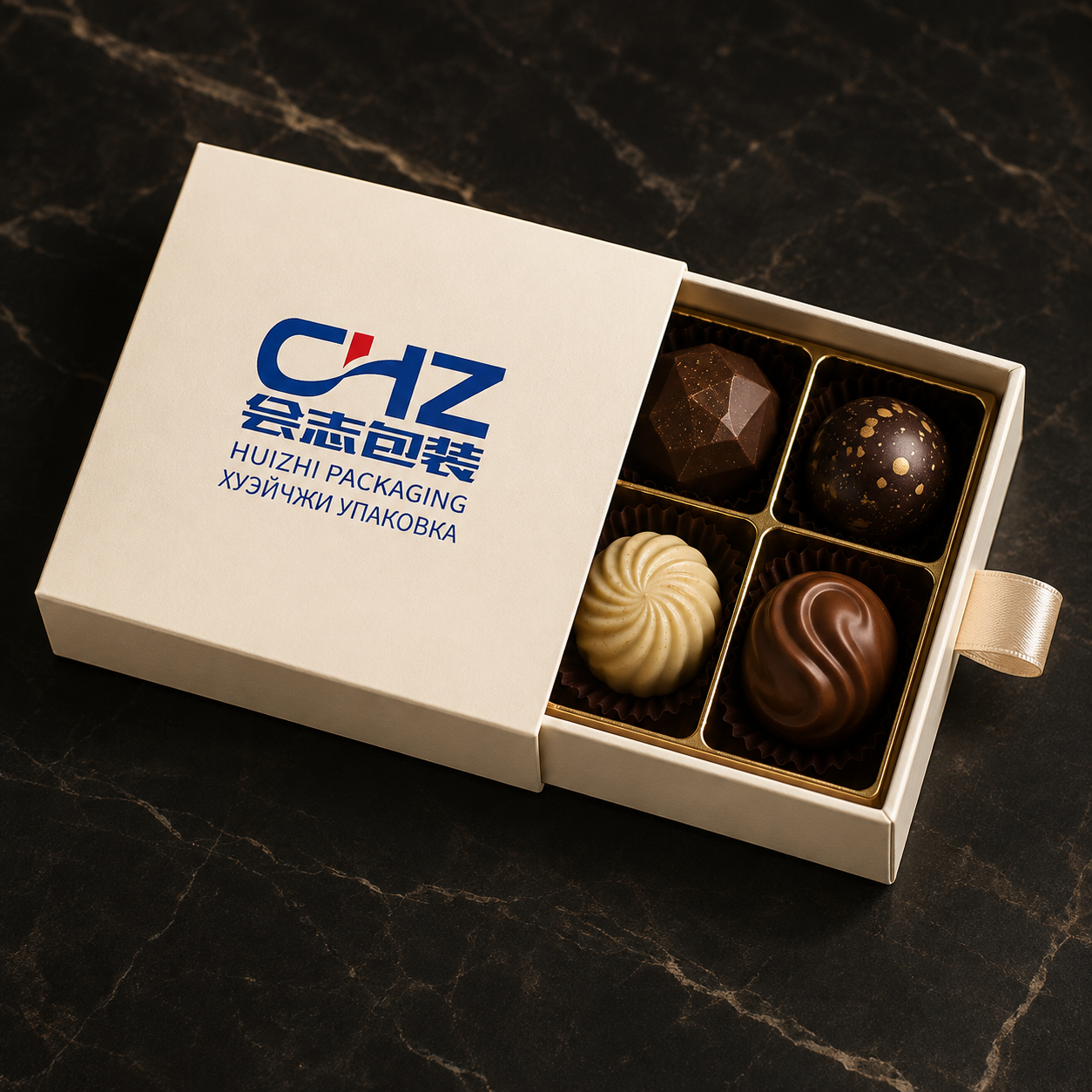 Partly open ivory drawer box with Huizhi Packaging branding and four artisan chocolates in a gold compartment tray.