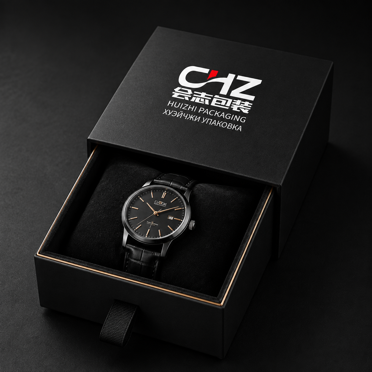 Open matte black rigid drawer box with Huizhi Packaging branding, ribbon pull, and wristwatch on a black cushion.