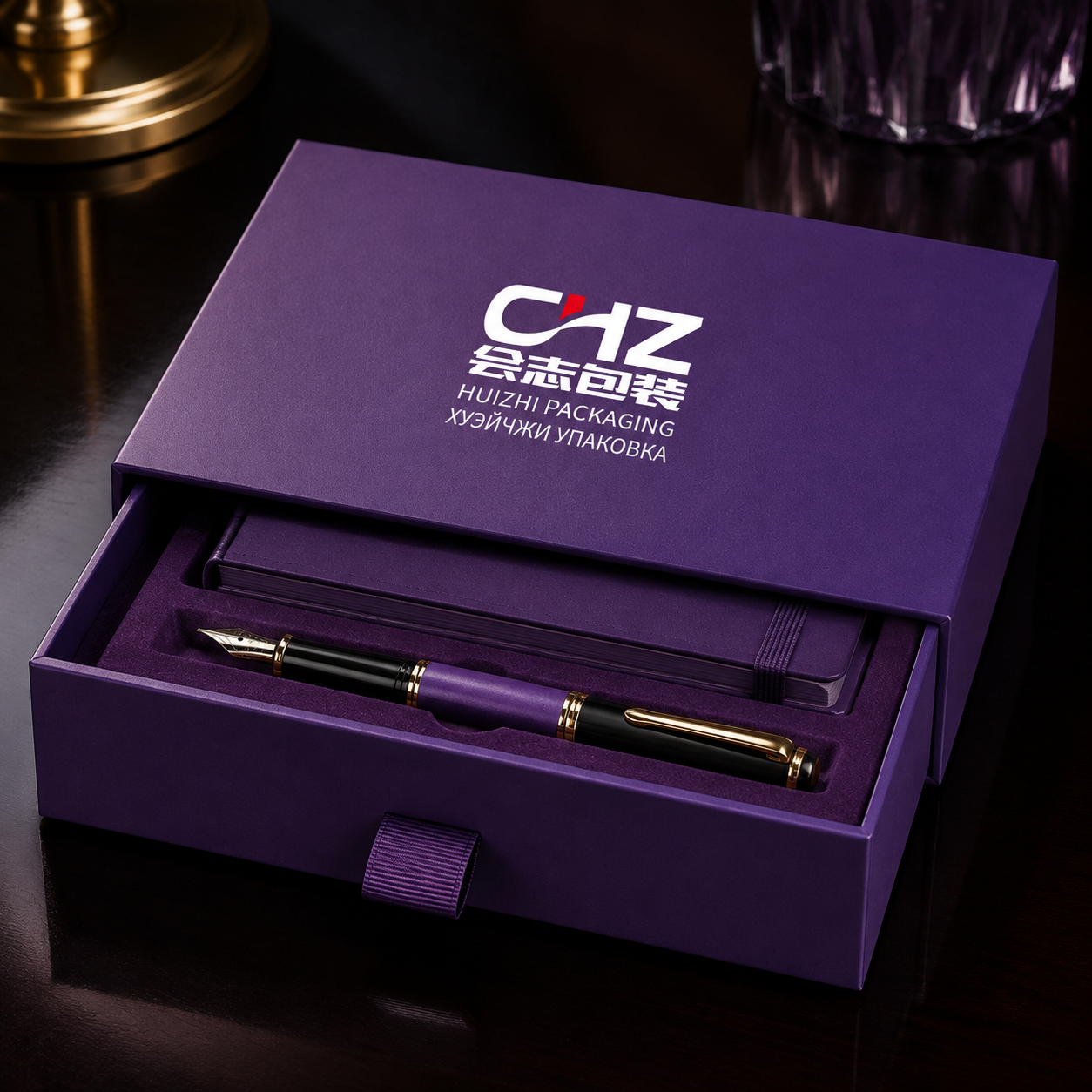 Open plum rigid drawer box with Huizhi Packaging branding, notebook, fountain pen, and fitted velvet insert.