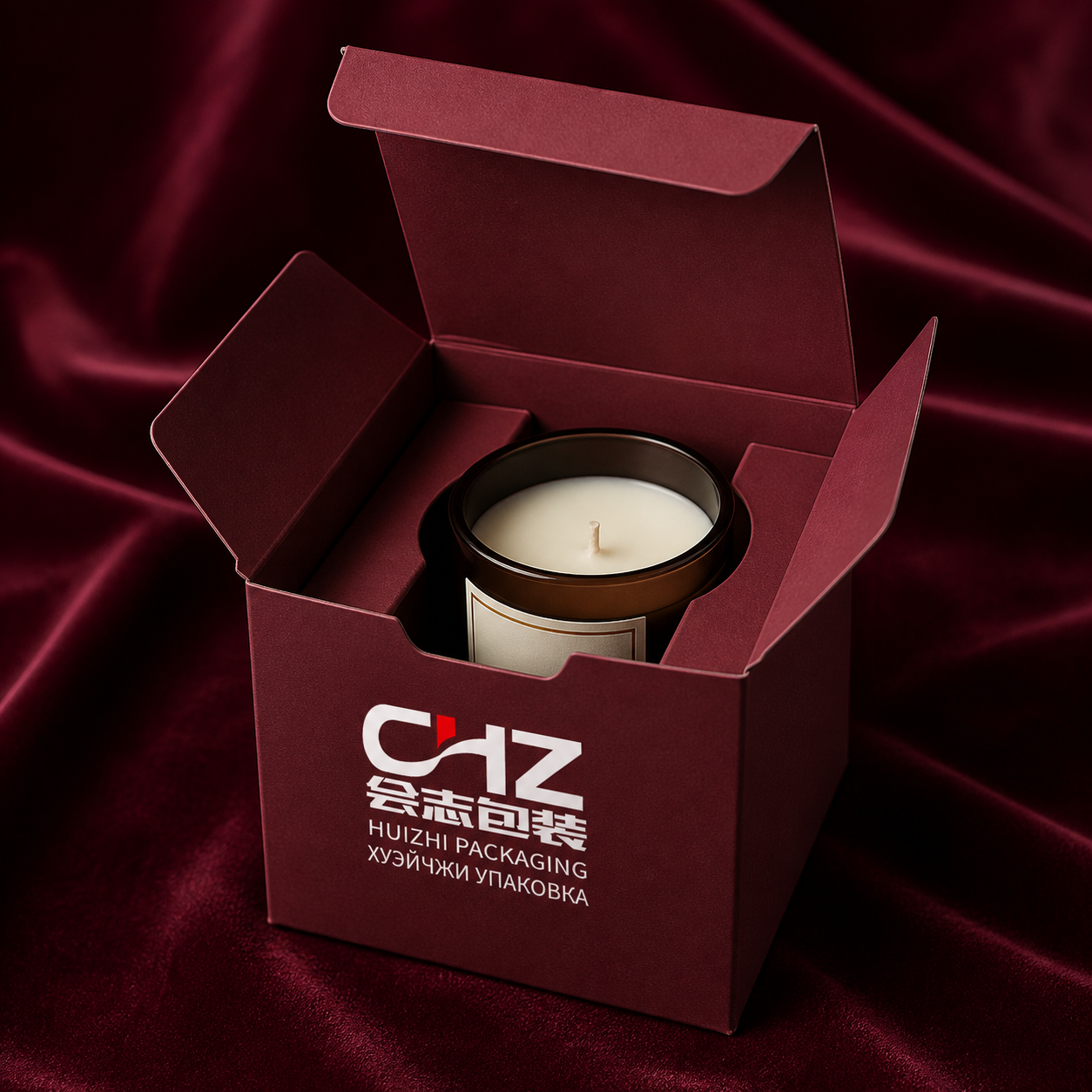 Open burgundy folding carton with Huizhi Packaging logo and folded paper supports around a glass candle jar.