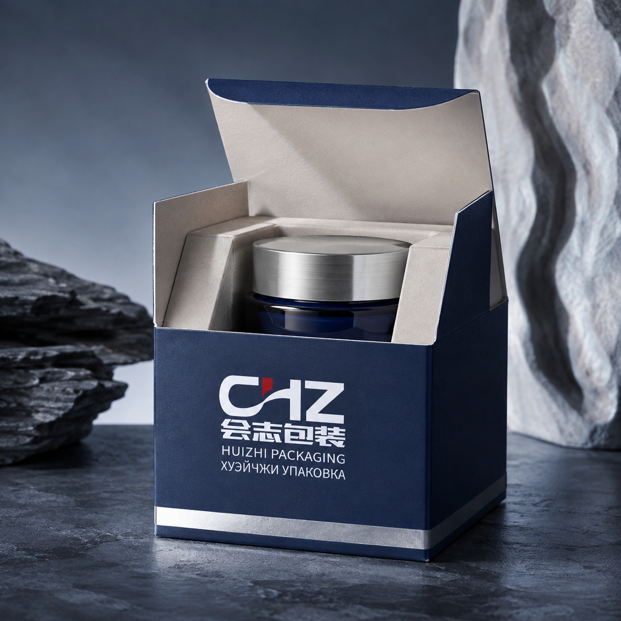 Open navy folding carton with Huizhi Packaging logo and raised paperboard supports holding a cosmetic cream jar.
