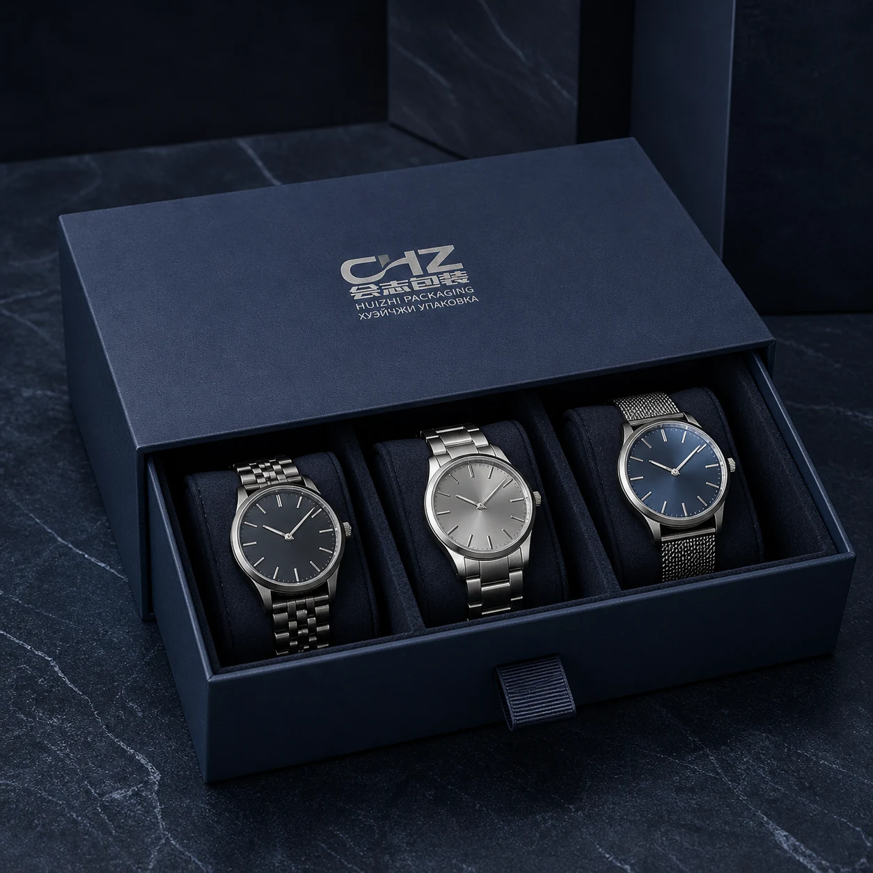 Open navy rigid drawer box with three fitted cushions holding three generic unbranded wristwatches.