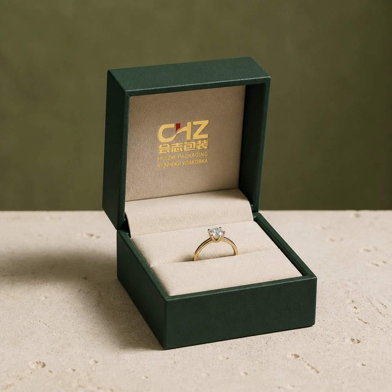 Open compact emerald green hinged ring box with a cream fitted insert holding one generic gemstone ring.