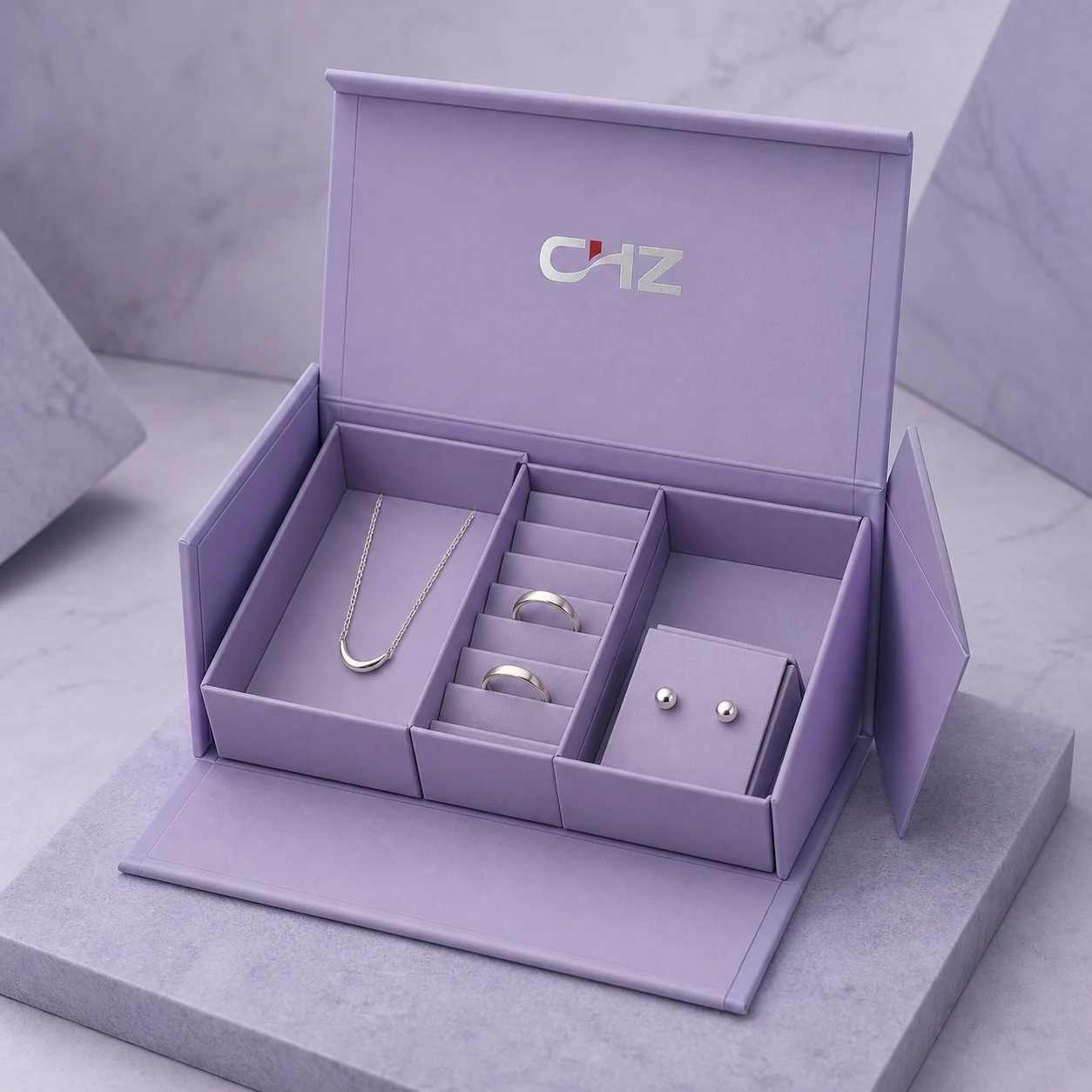 Open lavender collapsible magnetic jewelry organizer with removable compartments for a necklace, ring, and earrings.